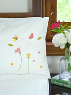 White pillowcase with embroidered bees, butterfly and pink and yellow flowers