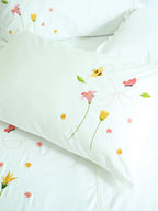 Close-up of white bed linen with bee, butterfly and floral embroidery