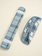Two blue plaid fabric handle covers with white lace trim and hook-and-loop tabs