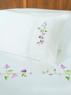 White pillowcase and bed sheet with pink and purple bougainvillea embroidery