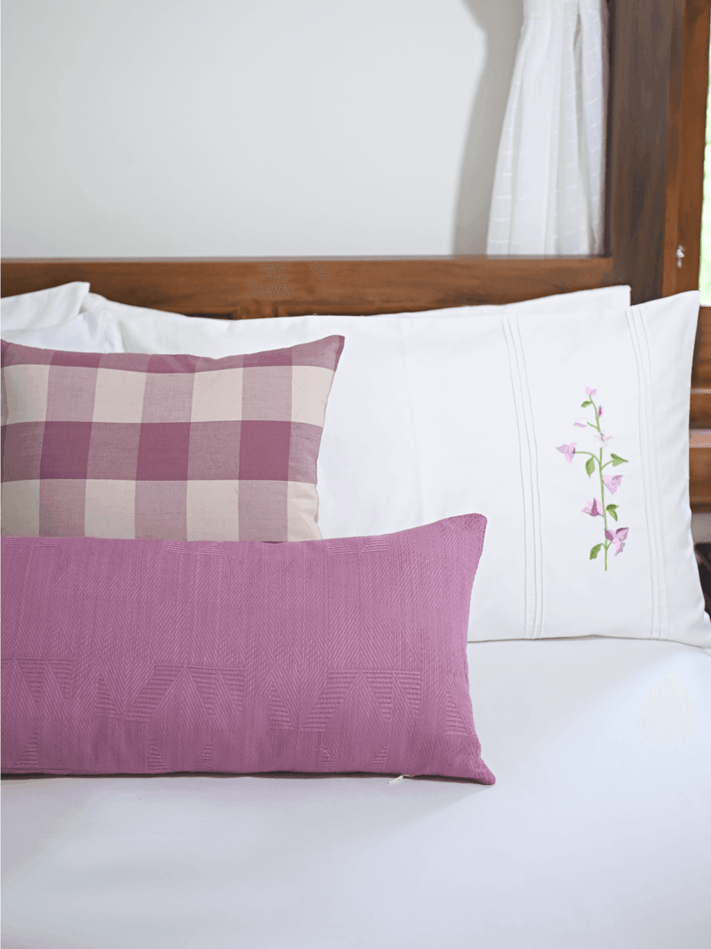 White bougainvillea embroidered pillowcase styled with mauve cushion covers