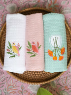 Three embroidered waffle hand towels in white, blush pink and mint green