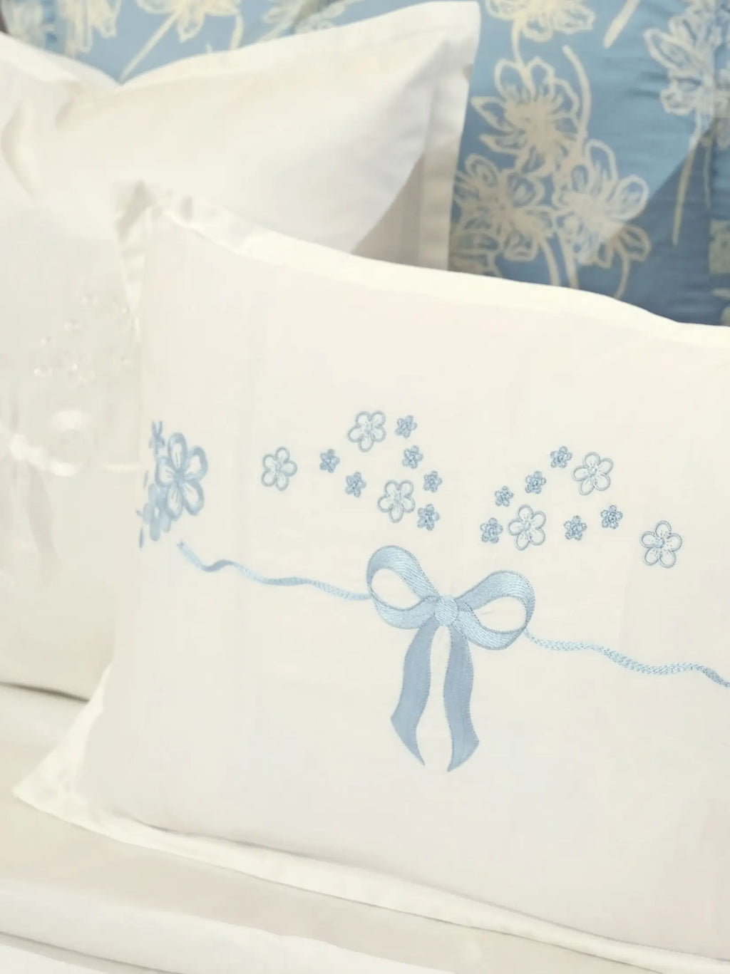 Close-up of a pale blue embroidered bow and flowers on a white cushion cover