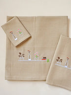 Cream honeycomb bath, hand and face towels with embroidered plants, flowers and books