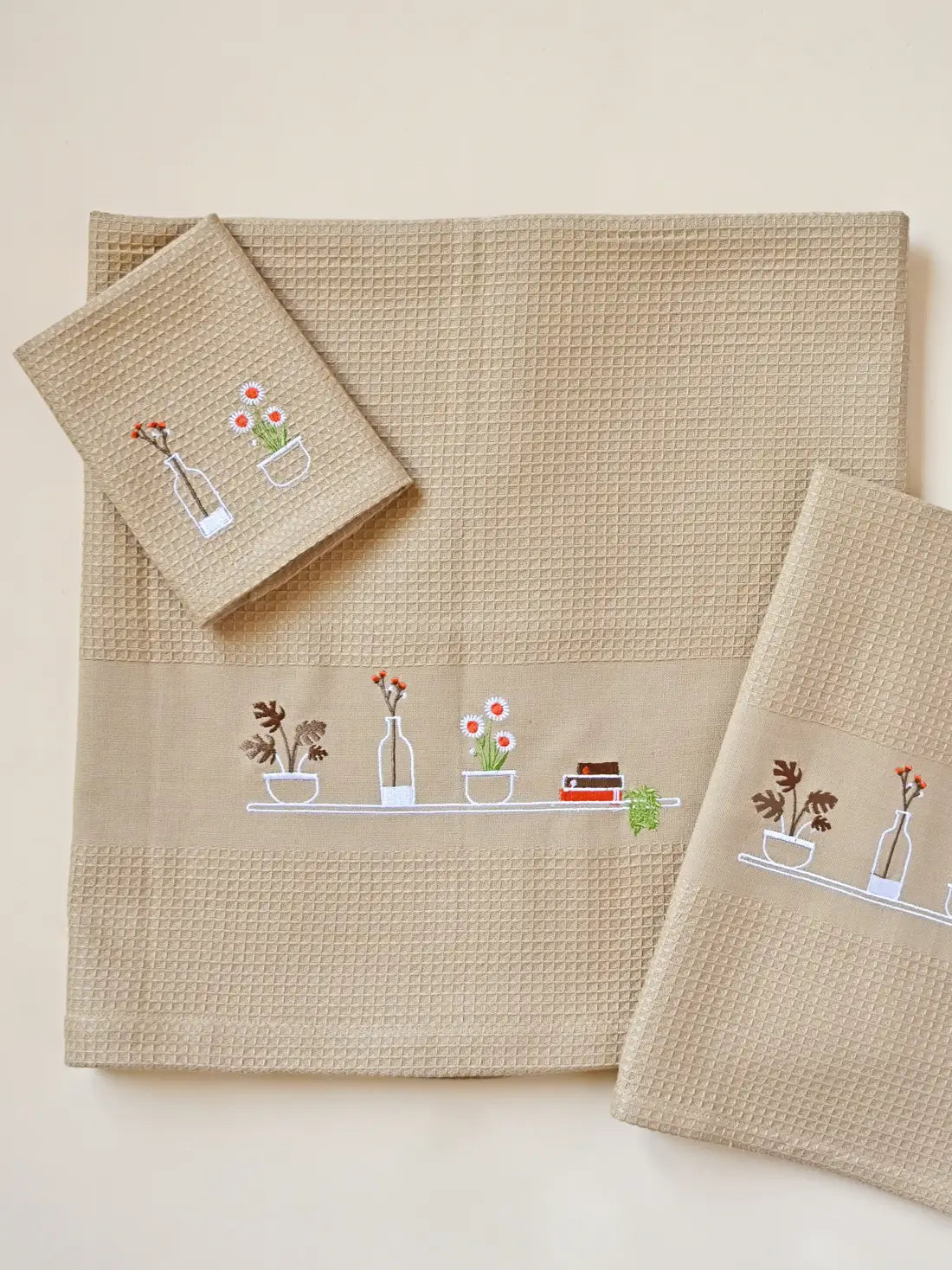 Cream honeycomb bath, hand and face towels with embroidered plants, flowers and books