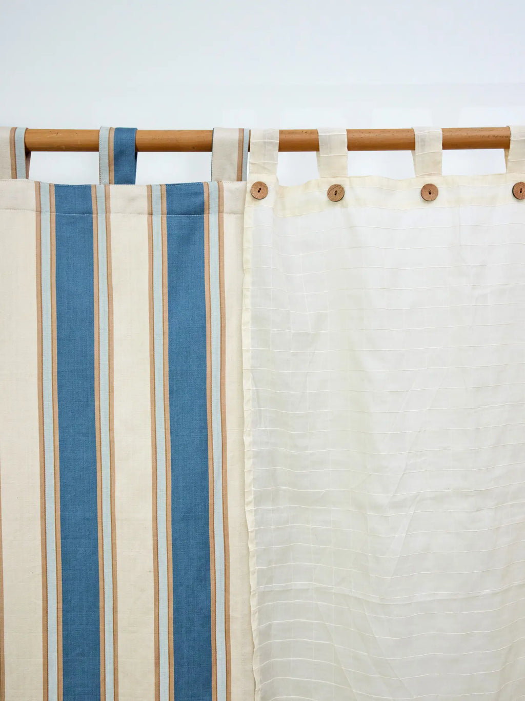 Ivory cream sheer checked curtain beside a blue striped curtain