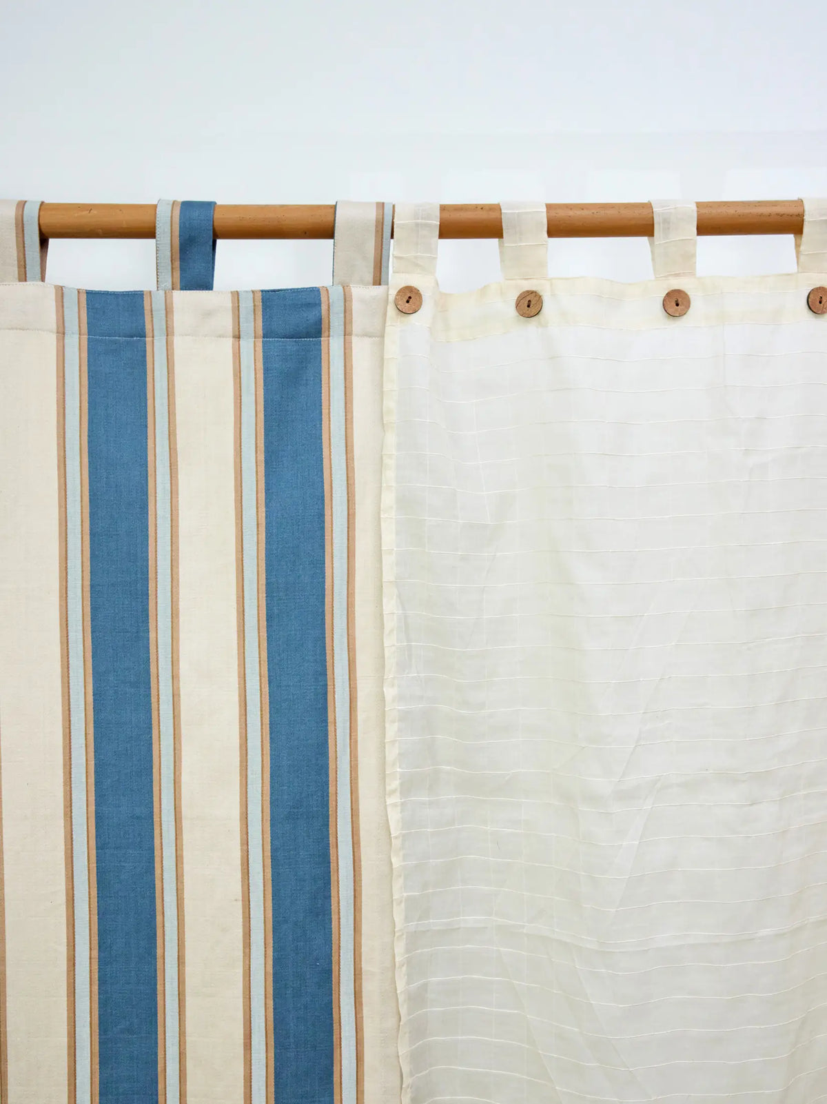 Ivory cream sheer checked curtain beside a blue striped curtain