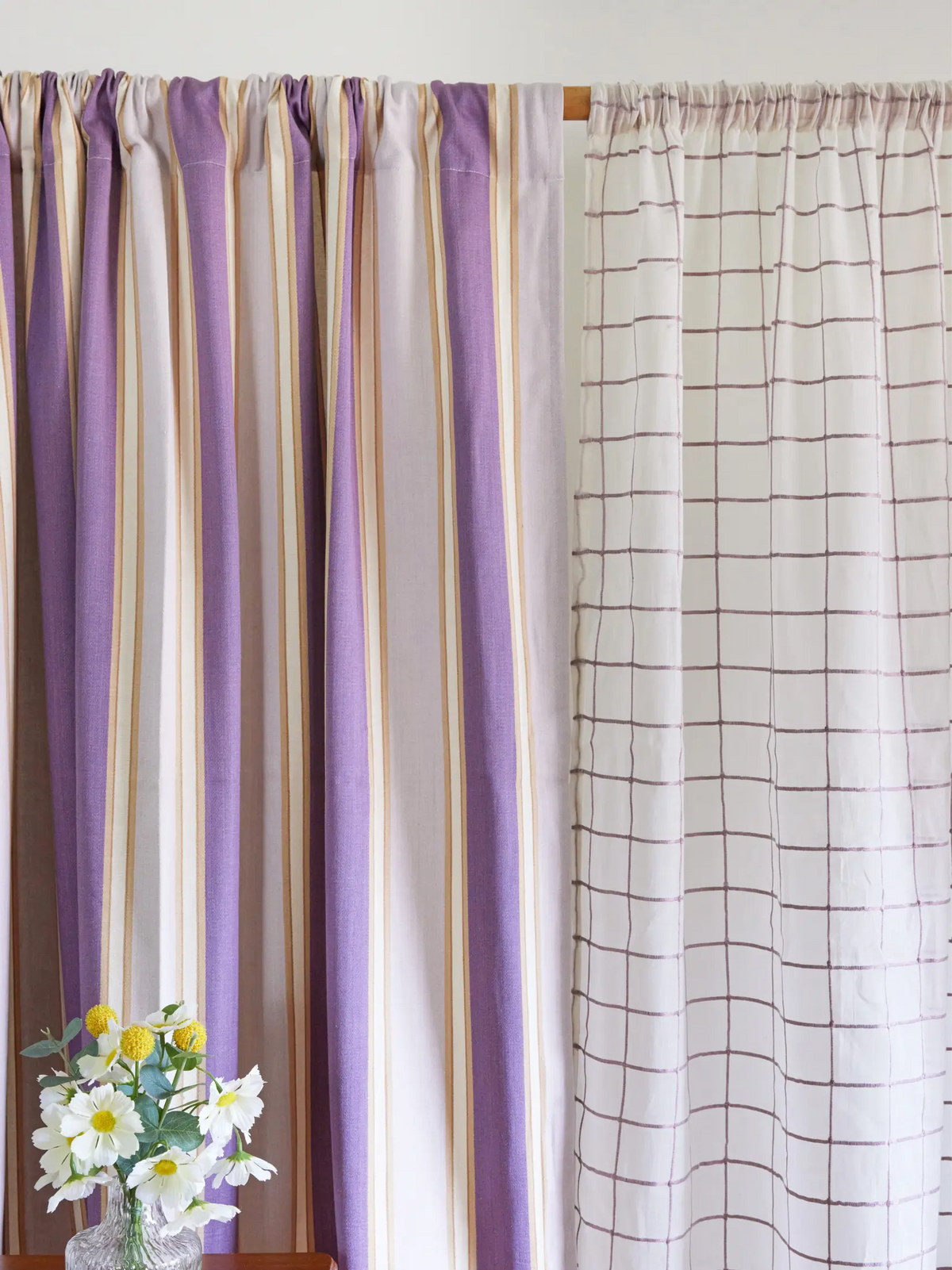 Lavender striped curtain beside a white curtain with a grey windowpane check