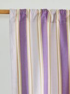 Close-up of a lavender, white and beige striped curtain gathered on a wooden rod