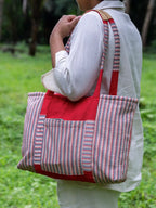Woman carrying a red, grey and white striped tote with a large outer pocket