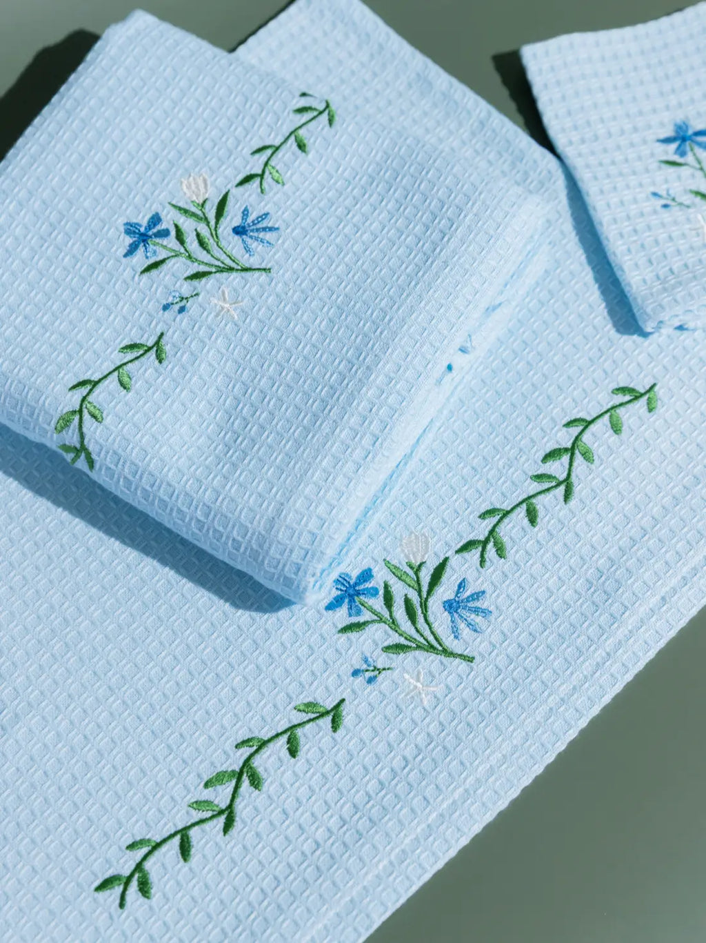 Close-up of blue and white floral embroidery on pale blue waffle towels