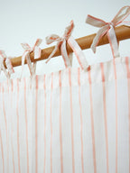 Close-up of fabric tie-top bows on a peach striped sheer curtain