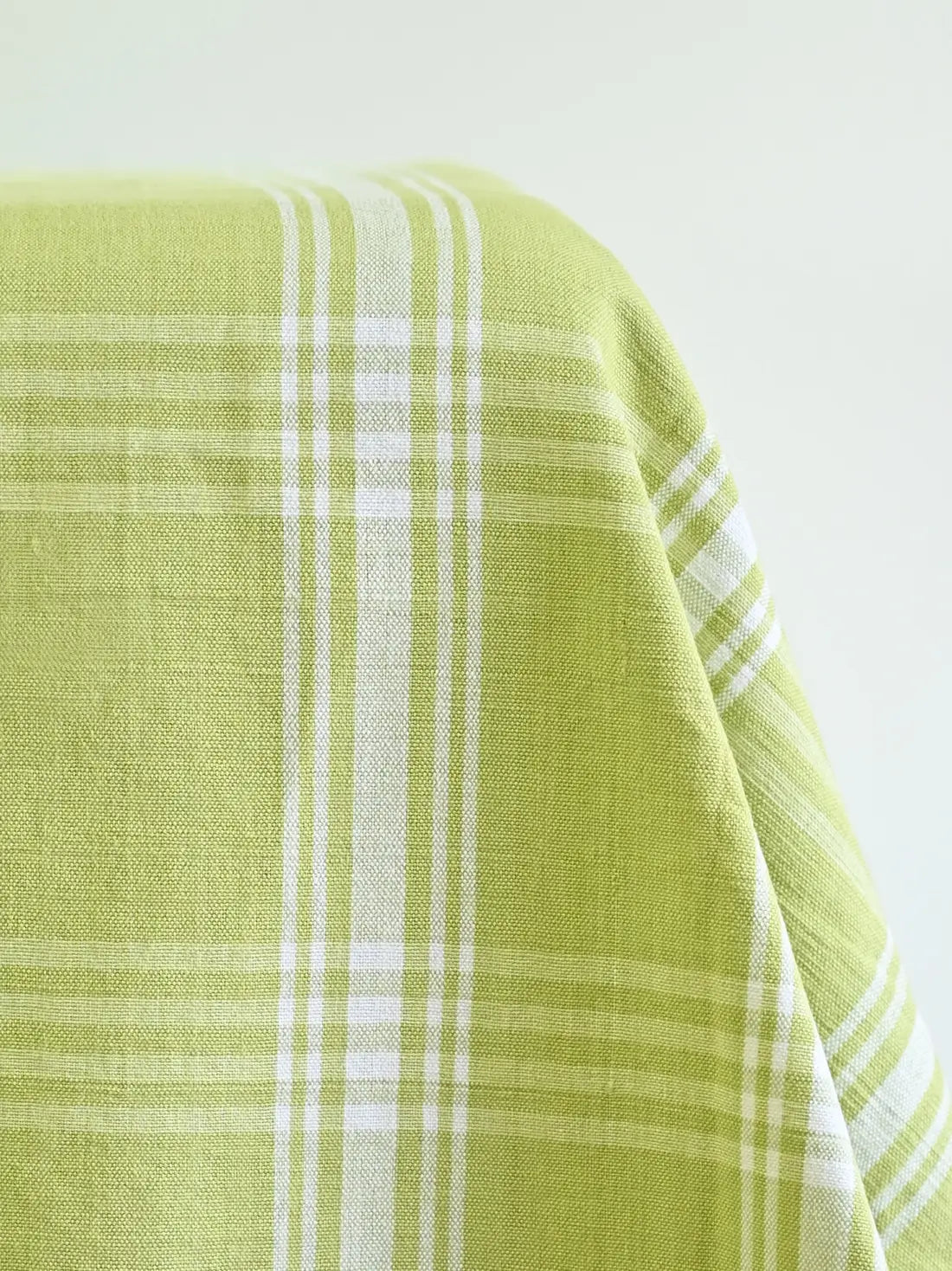 Close-up of light green woven tablecloth fabric with white plaid stripes