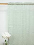 Full-length white sheer curtain with a fine green check pattern on a wooden rod