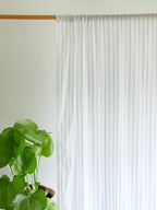 White sheer curtain with narrow powder blue stripes and a gathered rod pocket