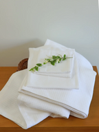 White waffle bath, hand and face towels stacked on a wooden table
