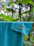 Close-up of tiger and pink flower embroidery on a teal blue waffle towel
