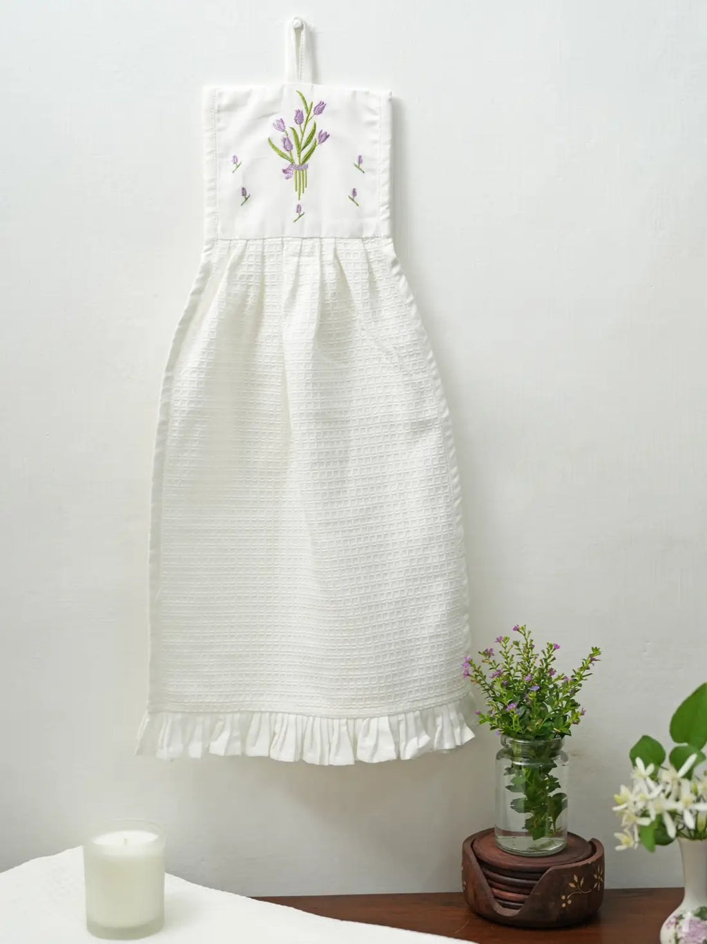 White hanging waffle hand towel with purple tulip embroidery and a ruffled hem