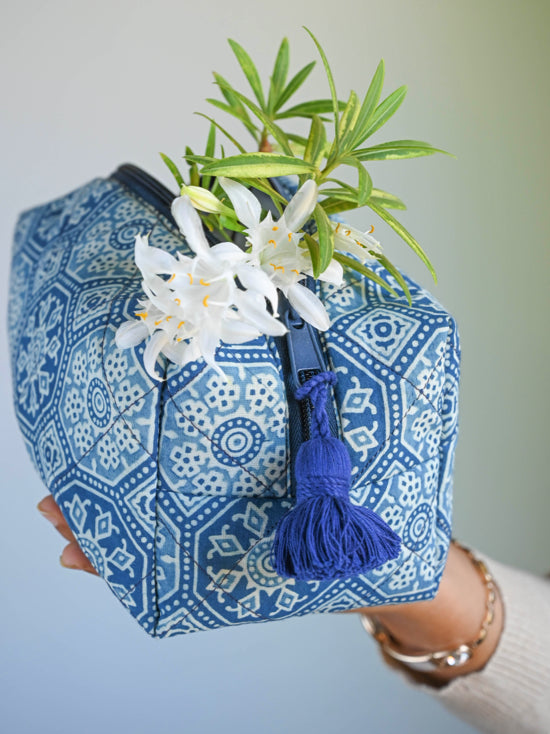 Close-up of a blue and white block-print toiletry bag with a black zip and blue tassel