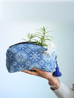 Hand holding a blue and white geometric block-print toiletry bag with a blue tassel